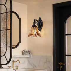 A bronze glass bell wall sconce mounted on a wall above a marble countertop, near a black door.