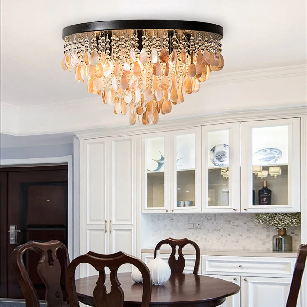 A gold and shell semi-flush mount ceiling light with multiple tiers of teardrop shapes hanging from a circular base, illuminating a dining room.