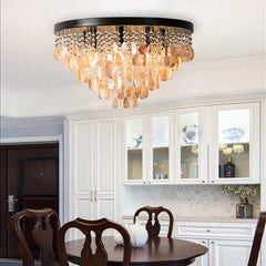 A gold and shell semi-flush mount ceiling light with multiple tiers of teardrop shapes hanging from a circular base, illuminating a dining room.