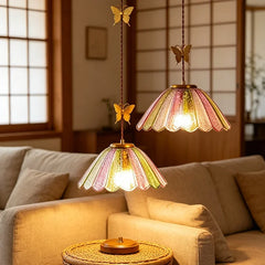 Two scalloped colored glass pendant lights with butterfly accents hanging above a sofa.