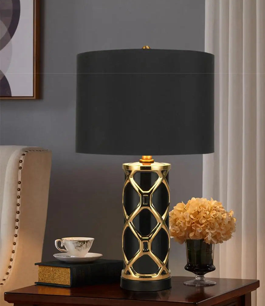 Decorative table lamp with black shade and gold accents on a wooden table.
