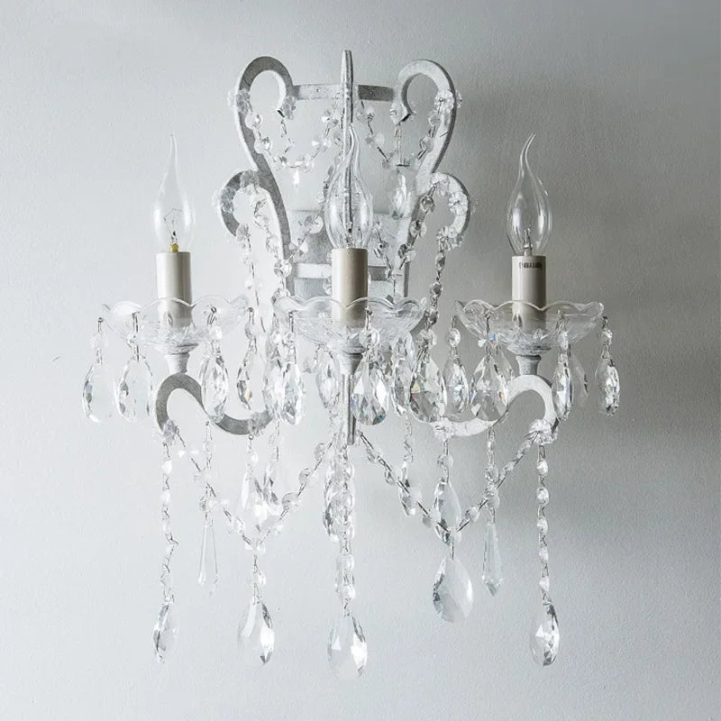 Crystal chandelier with three candle-style lights on a plain background