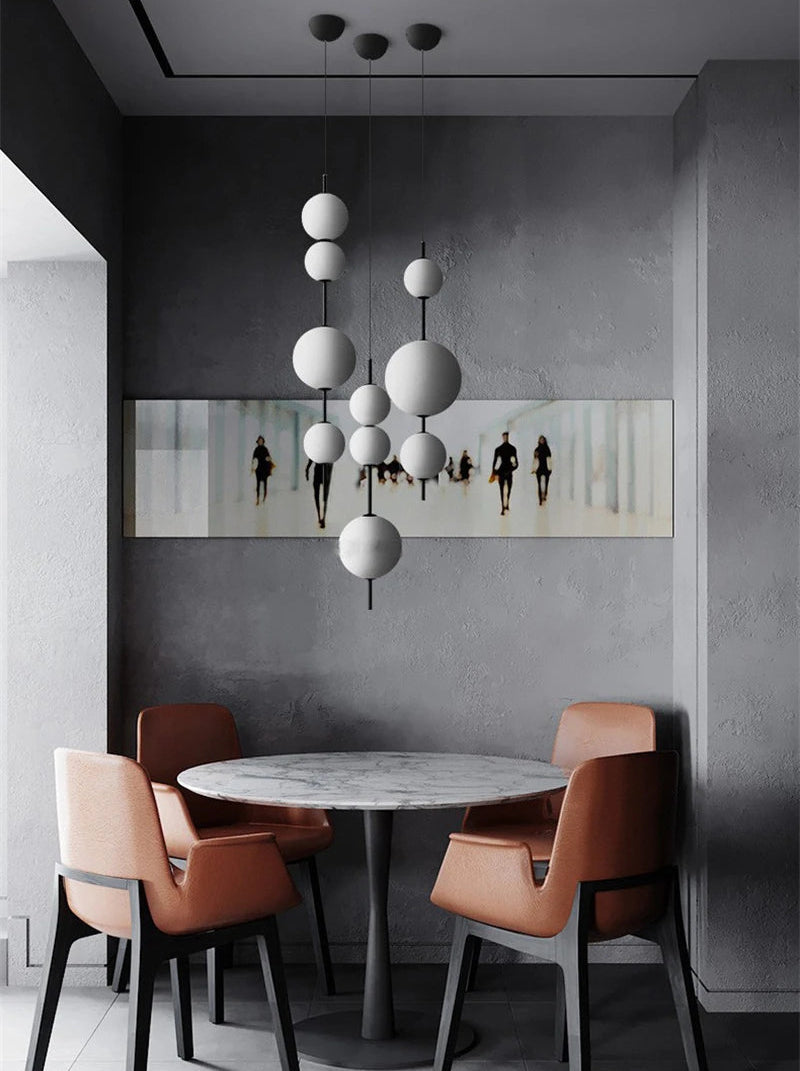 Modern dining area with a round table and chairs against a gray wall with a mirror.