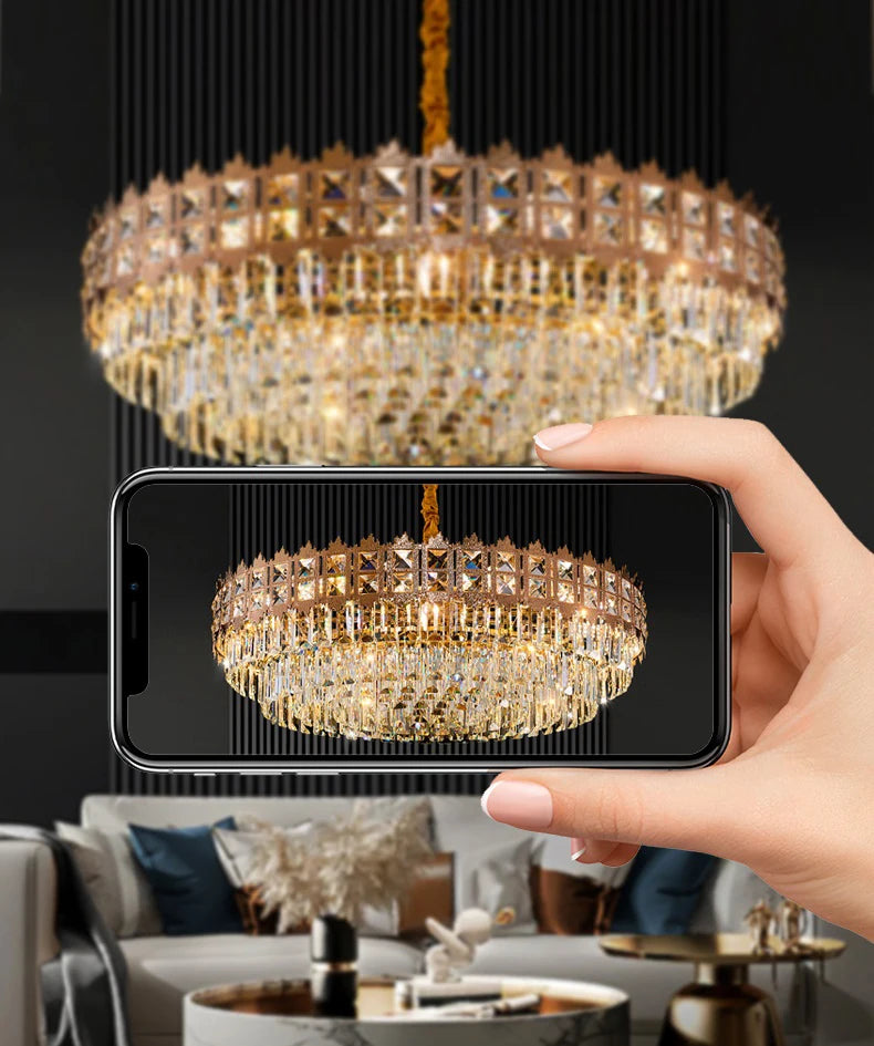Hand holding a smartphone displaying an image of a chandelier, with the actual chandelier in the background.