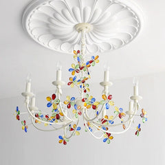 Angled view of a white chandelier with colorful crystal floral details and candle-style bulbs illuminating a room.