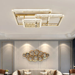 Gold geometric flush mount ceiling light with multiple rectangular frames adorned with clear crystals, installed in a living room above a sofa and art.