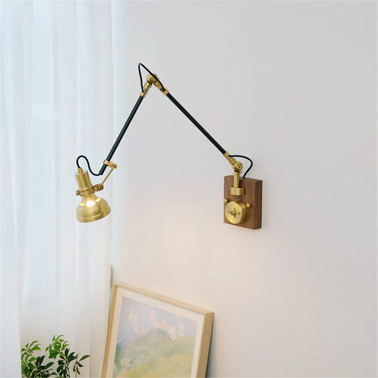 Brass adjustable swing arm wall sconce mounted on a white wall with a wooden base and knob switch.