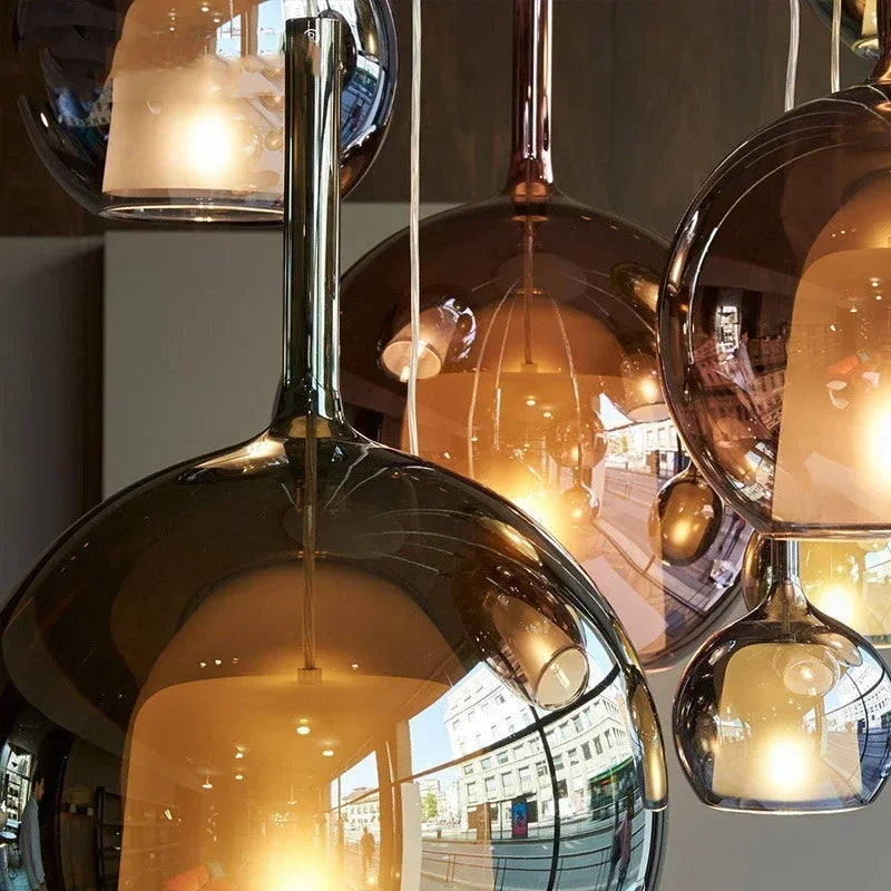 Close-up of multiple globe pendant lights with a smoked glass and rose gold finish, showing reflections of a city street.