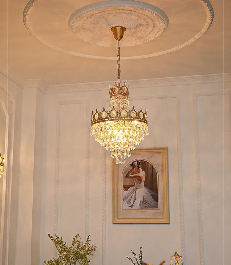 Chandelier hanging in a room with a portrait on the wall and decorative elements.