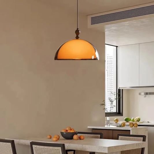 Amber glass dome pendant light hanging over a dining table