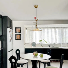 Kitchen area with a gold floral rose bud ceramic pendant light above a round table with chairs