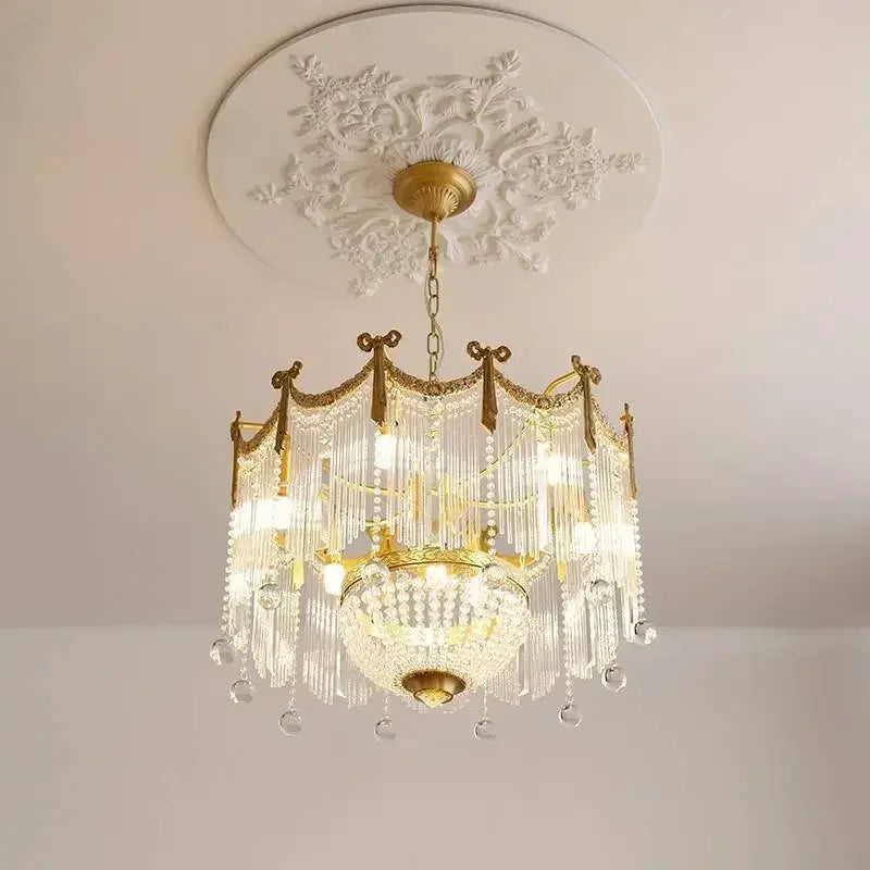 A gold crystal chandelier with cascading glass rods and orbs, suspended from a decorative ceiling medallion.