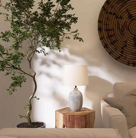 Living room with a tree, lamp, and woven wall art