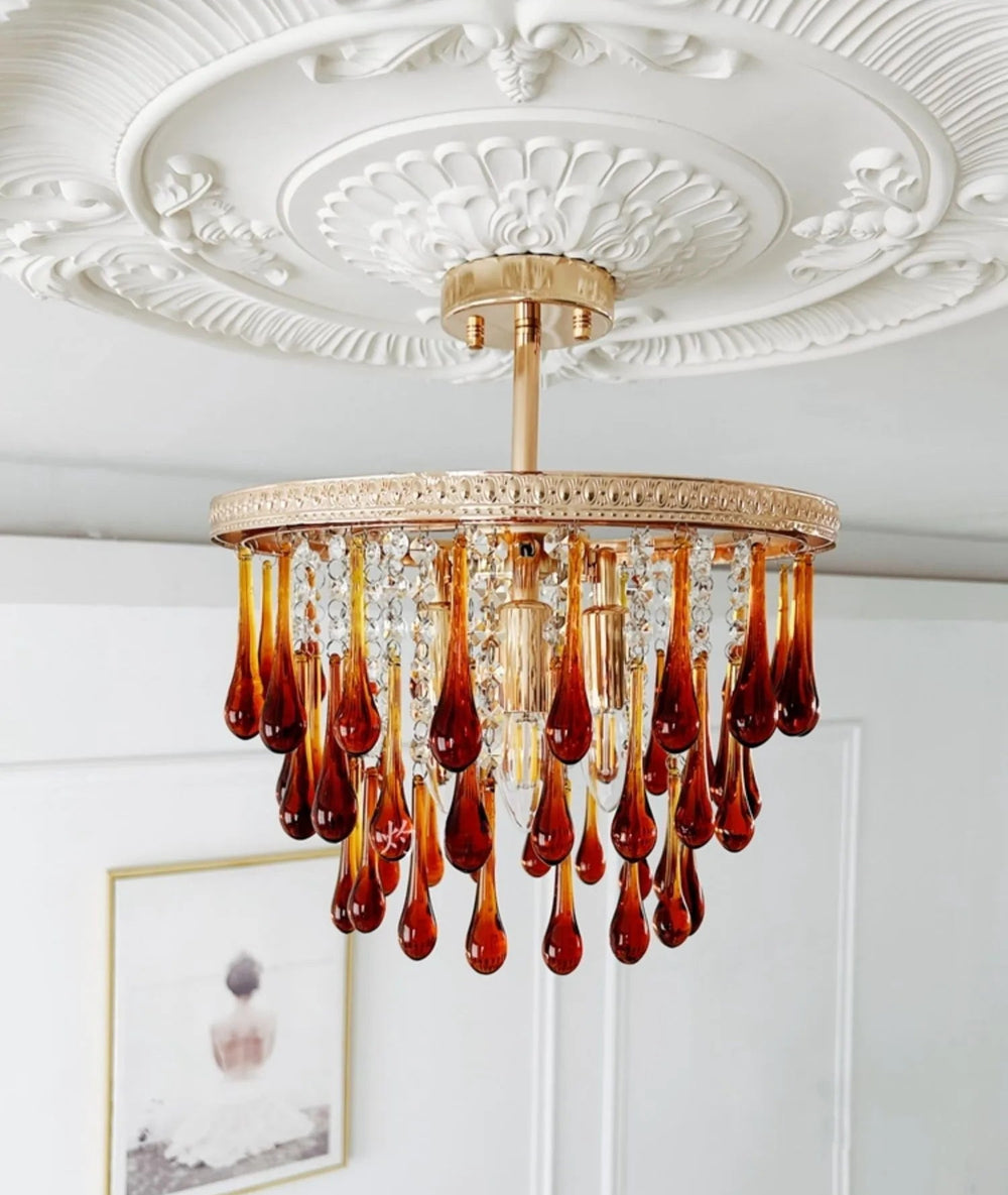 Chandelier with amber glass drops against a decorative ceiling