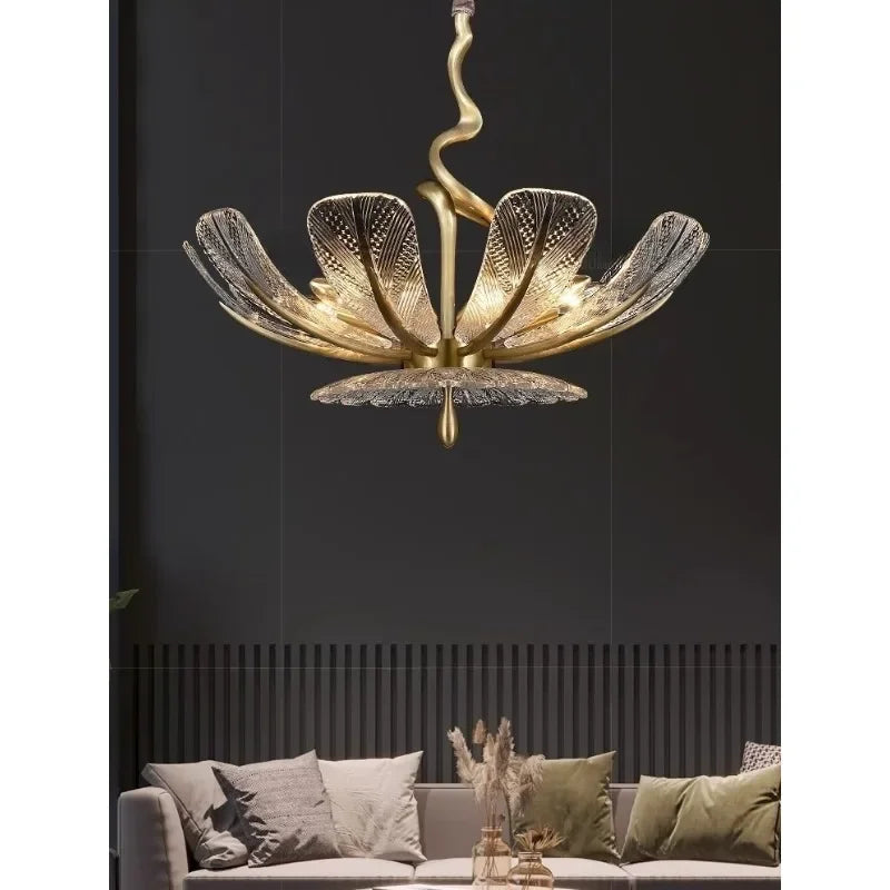 Interior setting showcasing a gold leaf floral chandelier with clear glass petals above a sofa.
