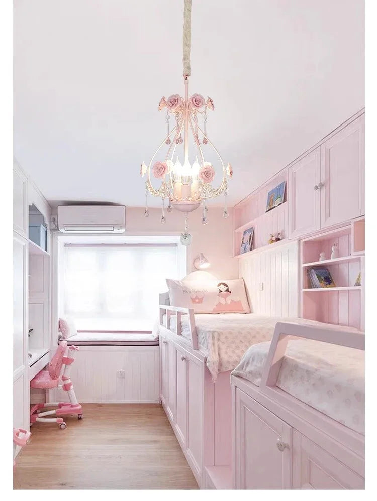 A pink crystal chandelier illuminates a brightly decorated child's bedroom with pink furniture and bunk beds.