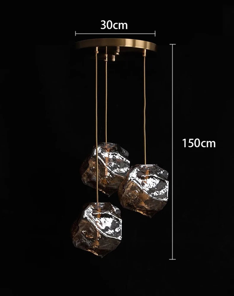 Pendant light with three rock-like glass elements and measurements on a black background