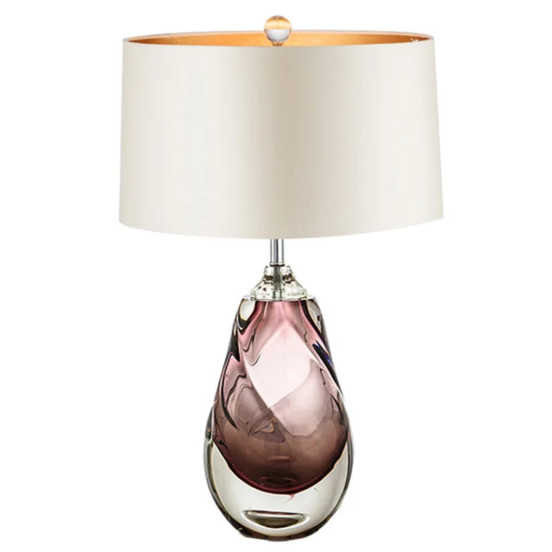 Purple glass swirl table lamp with a cream fabric shade on a white background