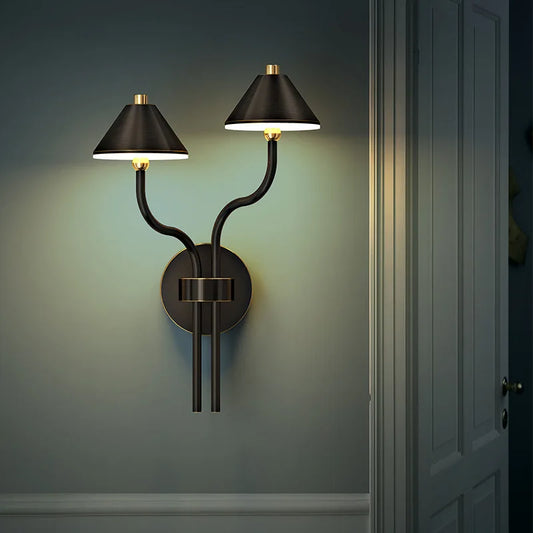 Close-up of a brass modern mushroom wall sconce with a warm light.