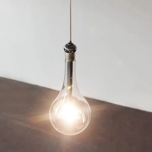 Close-up of a single clear glass teardrop pendant light, illuminated.