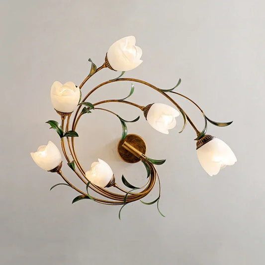 Close-up view of a white floral semi-flush ceiling light with a coiled gold-tone stem and green leaf accents.