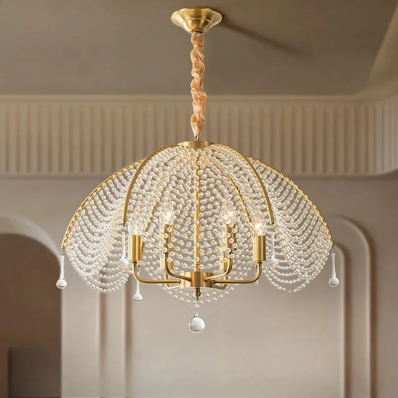 A gold crystal waterfall chandelier with a fabric-wrapped cord hanging from a ceiling.