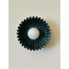 Dark green carved ceramic wall sconce with a white globe light in the center.