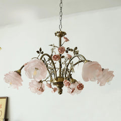 A brass chandelier with multiple pink rose bud and flower embellishments and frosted glass shades.
