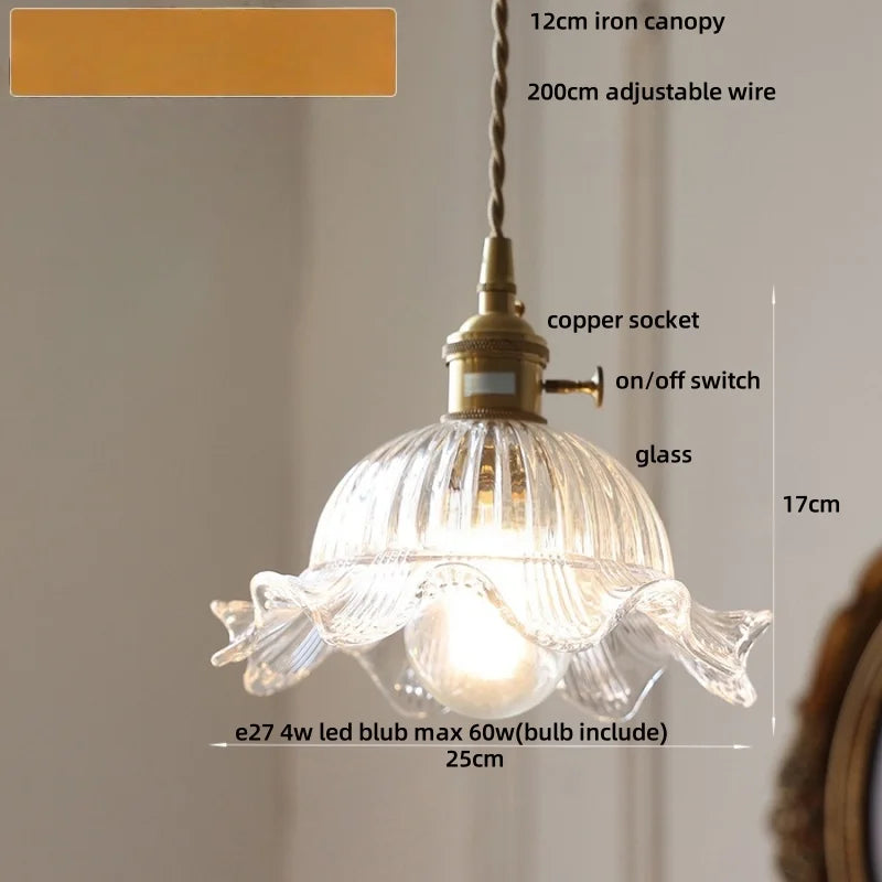 Pendant light with clear glass shade and brass fixture on a neutral background