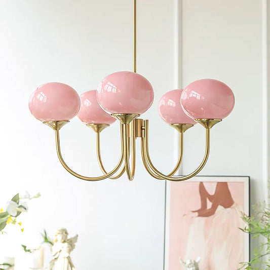 A close-up shot of a gold chandelier with five pink globe-shaped glass shades.