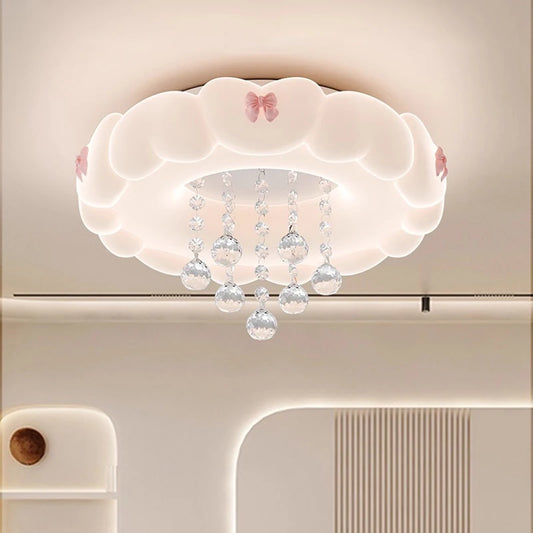 Close-up view of a white cloud-shaped ceiling light featuring pink bows and clear crystal accents, showing soft diffused lighting.