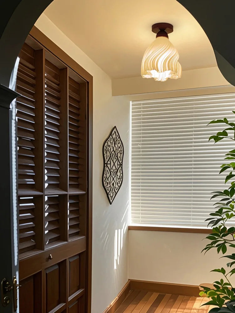 Room interior with wooden shutters, ceiling light fixture, and decorative wall art.