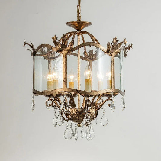 Close-up of a gold candelabra pendant light featuring a distressed gold frame, clear crystal accents, and a clear glass shade against a white background.