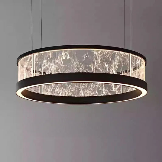 Close-up of a black ring-shaped pendant light with a textured glass diffuser, illuminated from within, against a dark background.