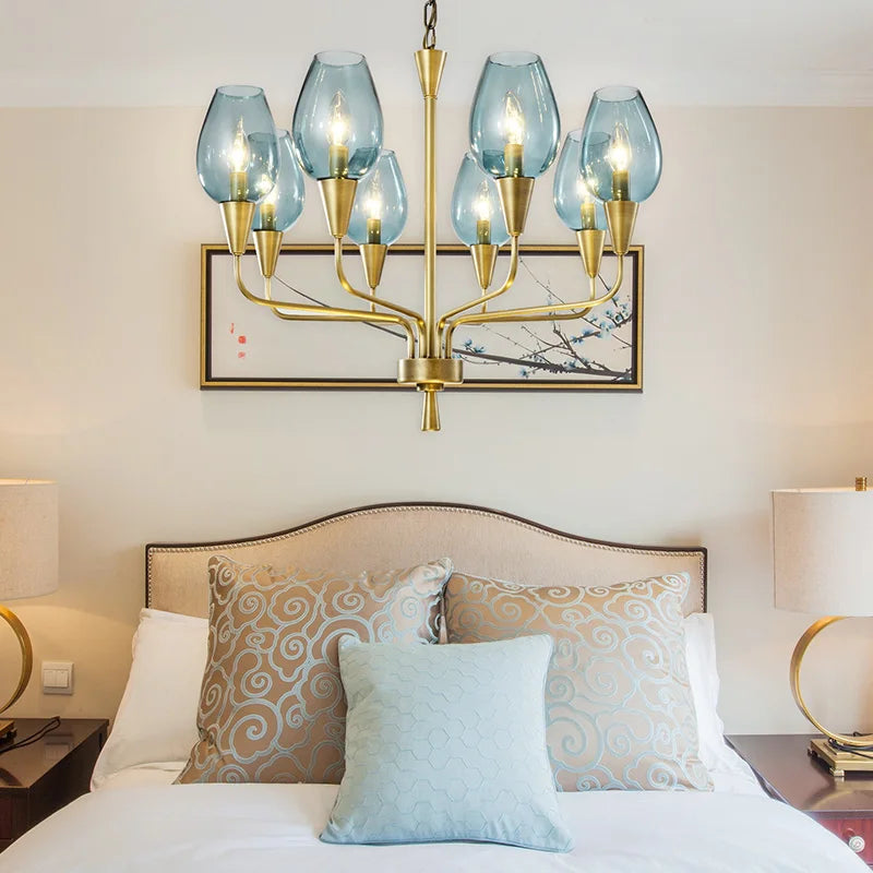 Gold chandelier with blue glass shades hanging above a bed in a bedroom.