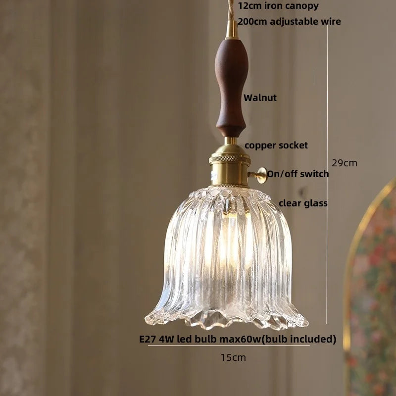 Pendant light with clear glass shade and wooden handle on a neutral background
