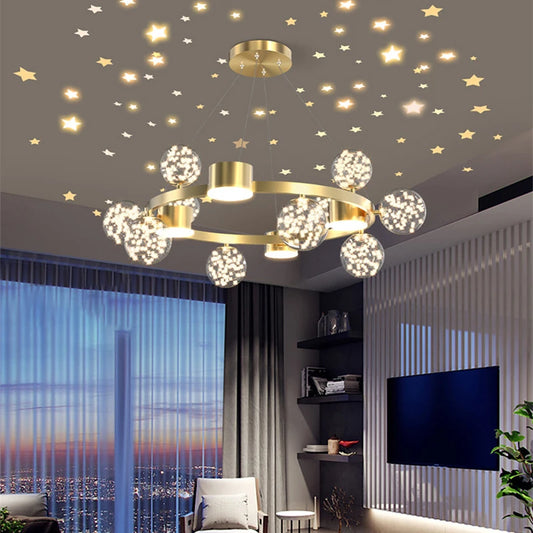 A gold starburst chandelier with glass orbs illuminated in a contemporary living room with a large window and city view.