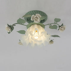 Close-up view of a green floral flush mount ceiling light with white roses and a ruffled glass shade with a visible E27 bulb socket.