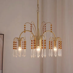 Close-up view of a gold chandelier featuring multiple arms adorned with clear crystal pendants and amber beads.