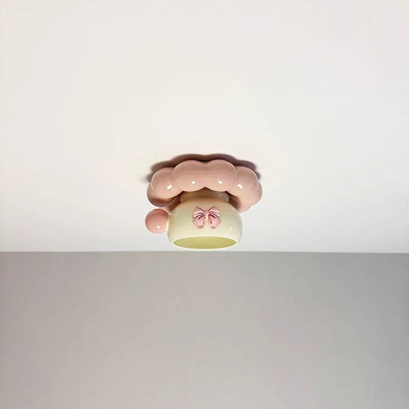 Frontal view of the pink ceramic coffee cup ceiling light mounted on a white ceiling, highlighting its whimsical design.