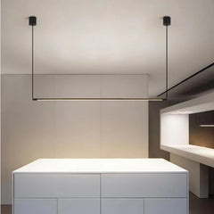 Black minimalist linear pendant light suspended over a kitchen island
