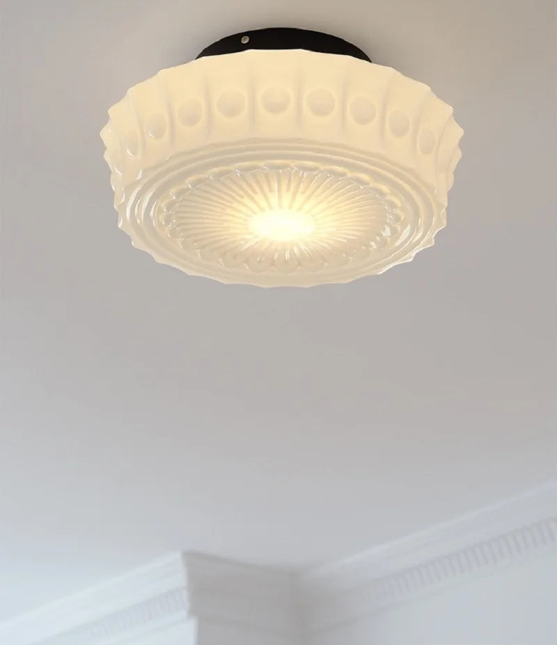 Ceiling light fixture with decorative glass shade on a plain ceiling