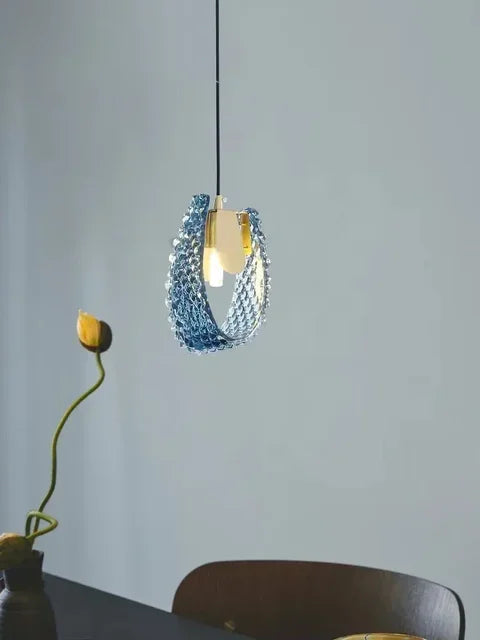 Modern pendant light with blue glass shade on a neutral background
