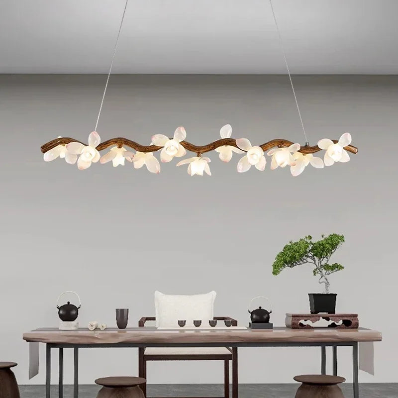 Modern chandelier hanging above a wooden table with a minimalistic interior design.