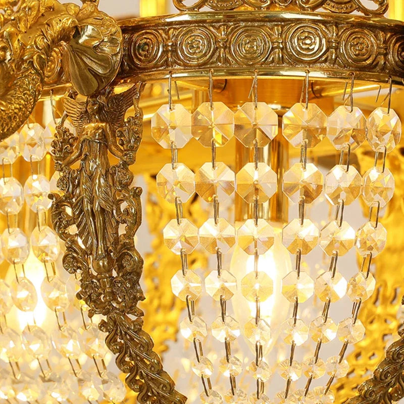 Close-up of the gold chandelier's crystal strands and decorative metalwork, with blurred lights in the background.