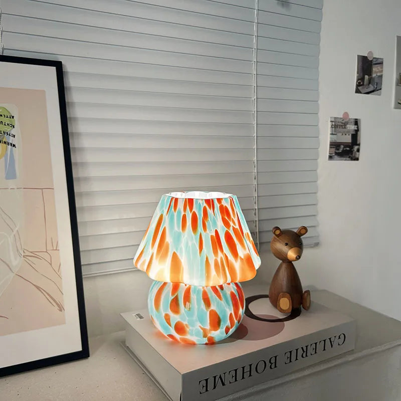 Colorful lamp on a book with a teddy bear next to it, in a room setting.