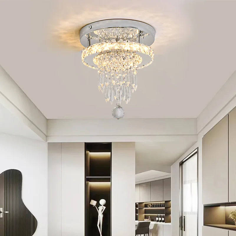 A chrome and crystal tiered ring flush mount ceiling light installed in a modern hallway with recessed lighting.