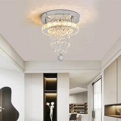 A chrome and crystal tiered ring flush mount ceiling light installed in a modern hallway with recessed lighting.