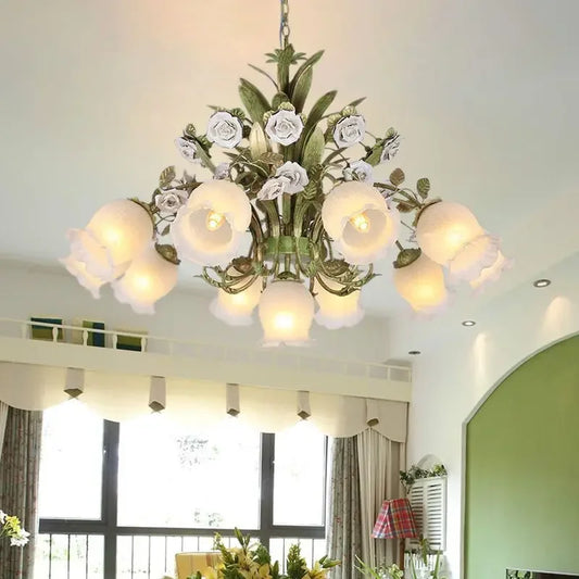 Close-up of a gold chandelier featuring intricate floral details with white ceramic roses and tulip-shaped frosted glass shades.