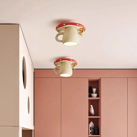 Two red and white mushroom-shaped ceiling lights with squirrel accents mounted on a pink ceiling in a room with pink cabinets.